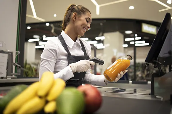 Operadora passando um produto no leitor, na esteira do caixa.
